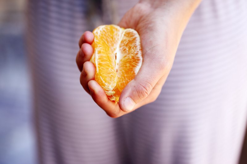 Hand zerdrückt eine halbe Orange
