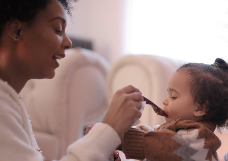 Flaschenwärmer erleichtern die Nahrungszubereitung Mama füttert Kind mit Brei