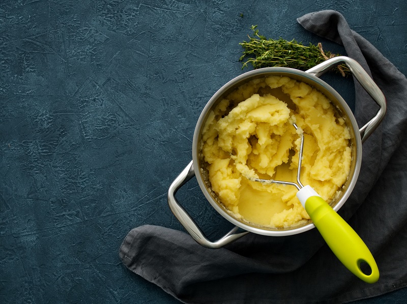 Kartoffelpüree in einem Topf mit Kartoffelstampfer