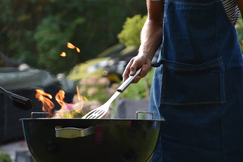 Eine grillende Person mit einem Pfannenwender in der Hand Pfannenwender aus Edelstahl wird beim Grillen verwendet