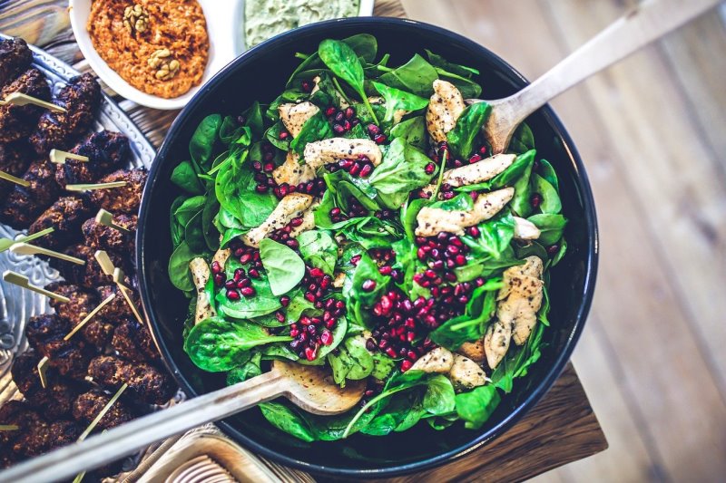 schwarze Salatschüssel mit Salat und Salatbesteck Schwarze Salatschüssel