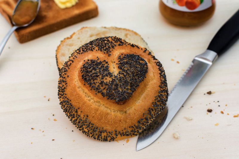 Brötchenmesser neben einem Brötchen mit Herz Brötchen mit Herz neben einem Messer