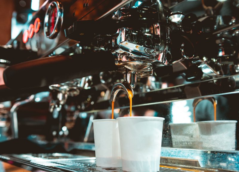 Espresso fließt aus dem Doppelausguss einer Siebträgermaschine in zwei Becher Ausguss einer Siebträgermaschine
