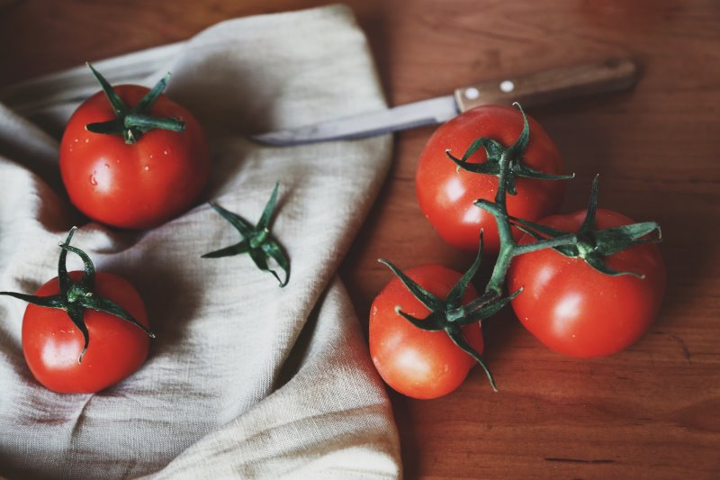 Tomatenmesser mit Tomaten Tomatenmesser liegt neben frischen Tomaten auf einem Geschirrtuch.